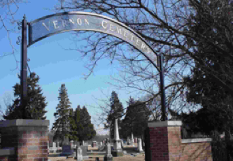An archway sign reads Vernon Cemetery.